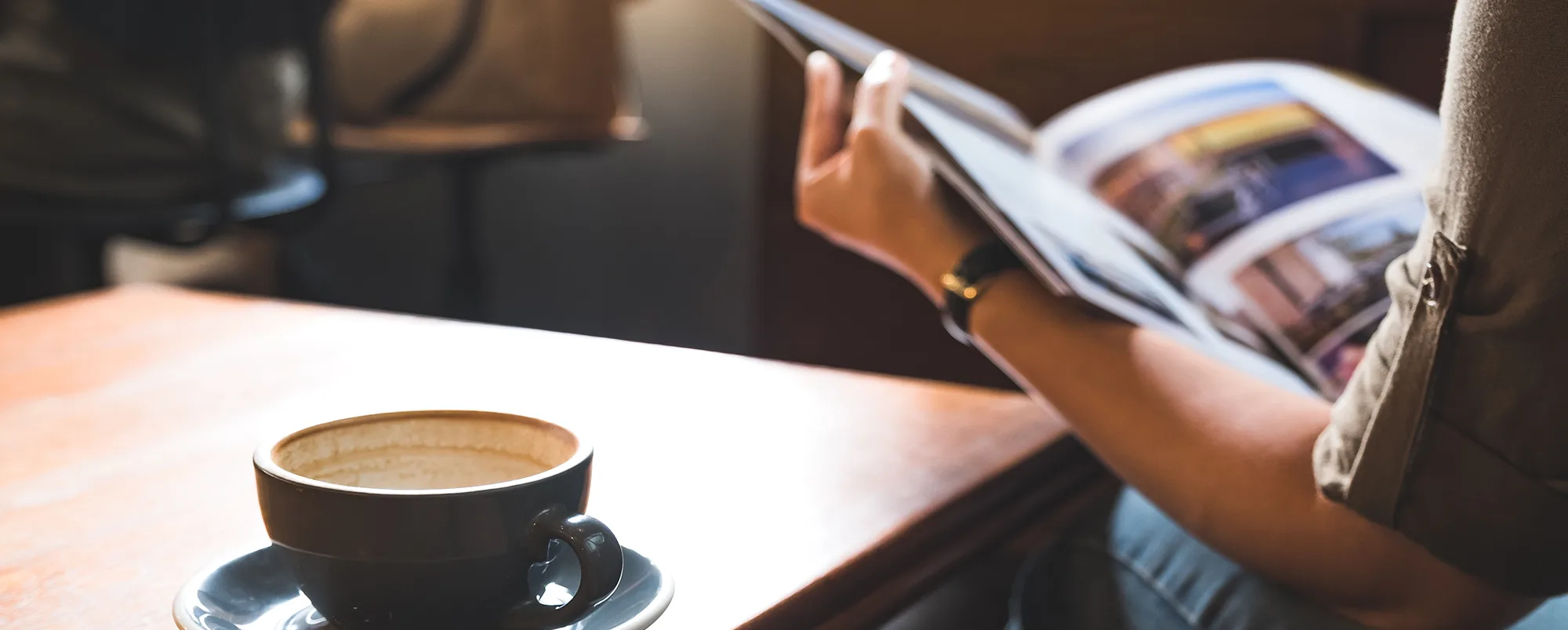 Closeup image of a woman reading a book with coffee cup on woode
